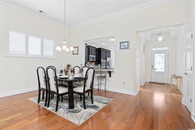 dining space featuring an inviting chandelier, ornamental molding, and light hardwood / wood-style flooring