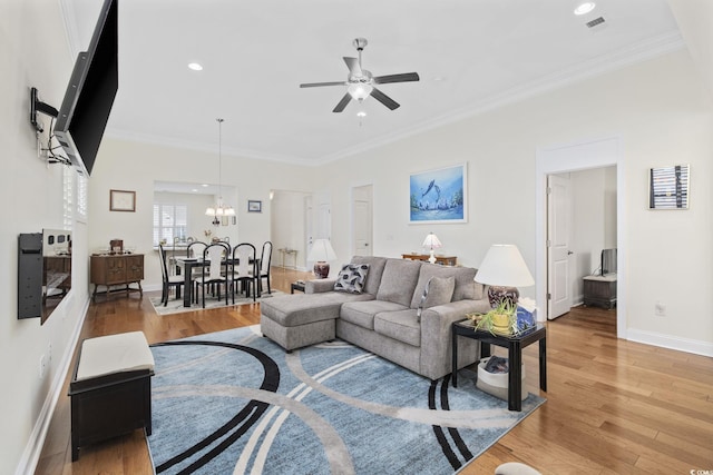 living room with crown molding, wood-type flooring, and ceiling fan with notable chandelier