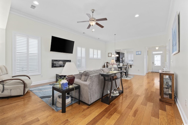 living room with ceiling fan, ornamental molding, and light hardwood / wood-style floors