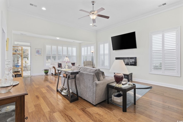 living room featuring crown molding, a wealth of natural light, ceiling fan, and light hardwood / wood-style flooring