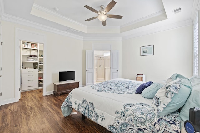 bedroom featuring ornamental molding, dark wood-type flooring, ceiling fan, and a tray ceiling