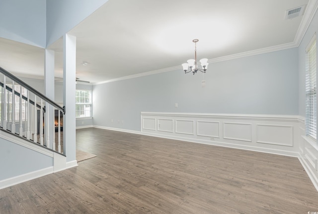 empty room featuring crown molding, wood-type flooring, and a chandelier