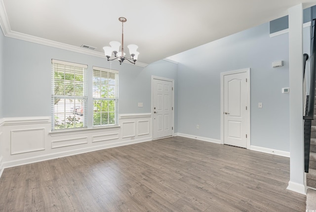 unfurnished room featuring an inviting chandelier, hardwood / wood-style floors, and ornamental molding