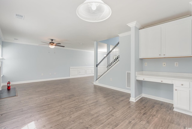 interior space with crown molding, ceiling fan, built in desk, and light hardwood / wood-style floors