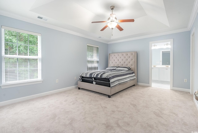 carpeted bedroom featuring a tray ceiling, crown molding, ceiling fan, and ensuite bathroom