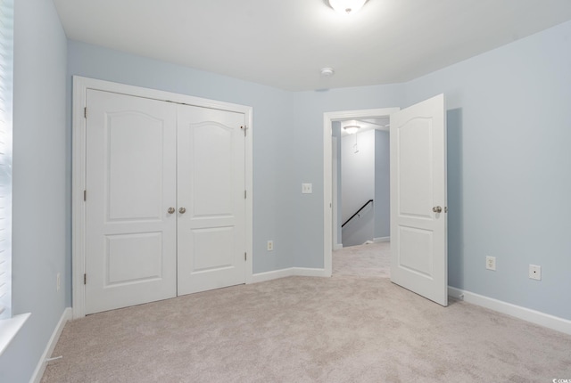 unfurnished bedroom featuring light colored carpet and a closet