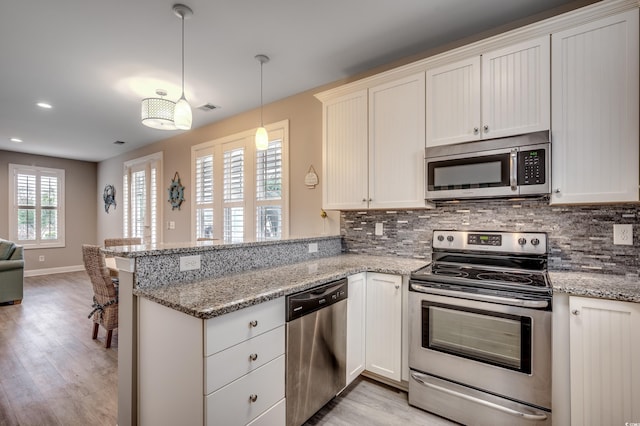 kitchen featuring stainless steel appliances, light wood-type flooring, kitchen peninsula, and hanging light fixtures