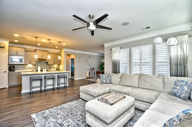 living room with dark wood-type flooring, ceiling fan, and ornamental molding