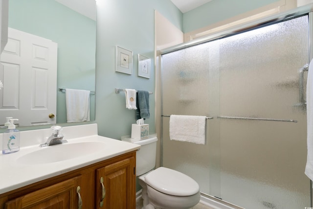 bathroom featuring a shower with shower door, vanity, and toilet