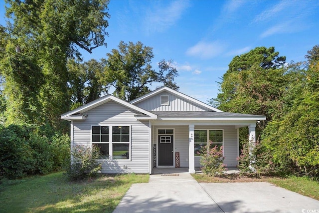 bungalow with covered porch and a front lawn