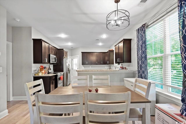 dining area with sink, a notable chandelier, and light wood-type flooring