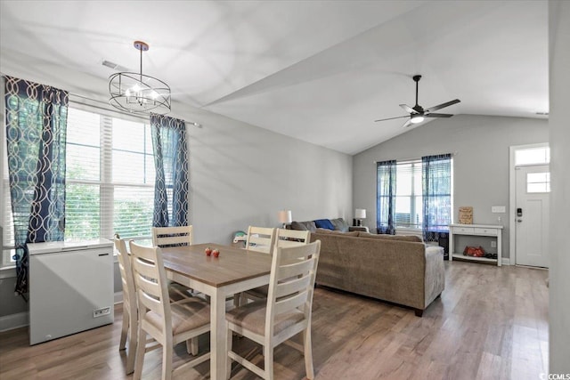 dining room featuring hardwood / wood-style flooring, vaulted ceiling, and ceiling fan with notable chandelier