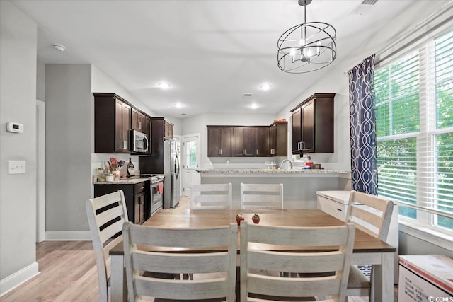 dining space featuring light wood-type flooring, a chandelier, and a healthy amount of sunlight