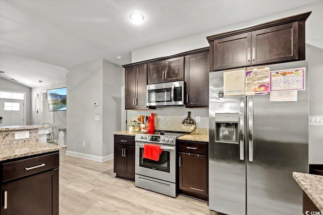 kitchen with light stone countertops, dark brown cabinets, stainless steel appliances, and light hardwood / wood-style floors