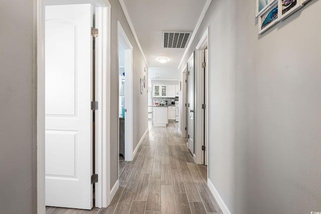 hallway with light hardwood / wood-style floors and crown molding