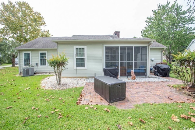 rear view of house with a lawn, a sunroom, central AC, and a patio area