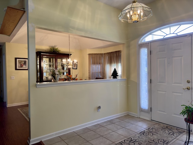 tiled entryway featuring a notable chandelier