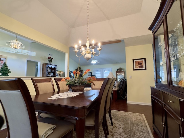 dining area with vaulted ceiling, a notable chandelier, and dark hardwood / wood-style flooring