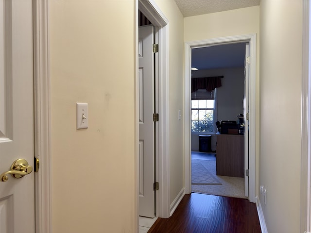 corridor with a textured ceiling and dark wood-type flooring