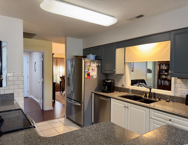 kitchen with backsplash, sink, white cabinetry, appliances with stainless steel finishes, and light tile patterned floors