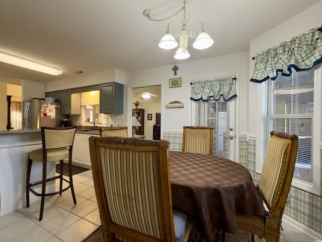 tiled dining room featuring sink, a chandelier, and a textured ceiling