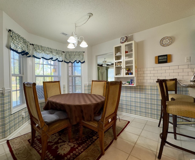 dining room with light tile patterned floors, ceiling fan with notable chandelier, and a textured ceiling