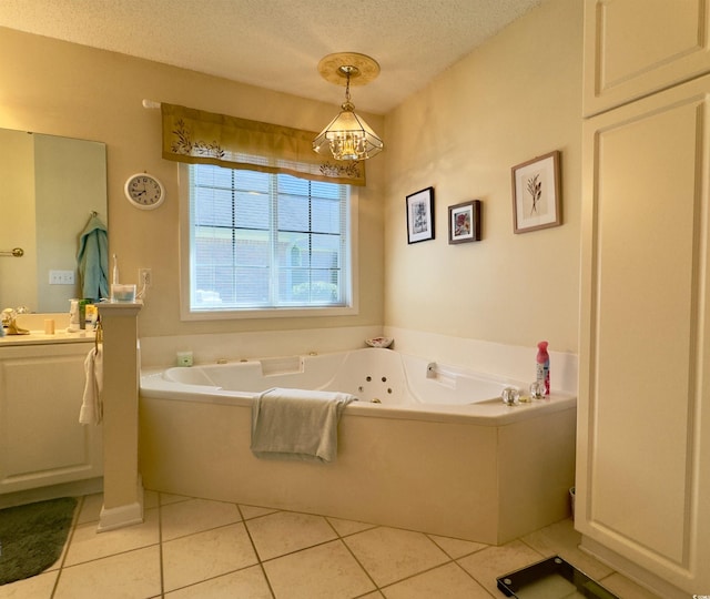 bathroom with a textured ceiling, tile patterned flooring, vanity, a notable chandelier, and a bathing tub