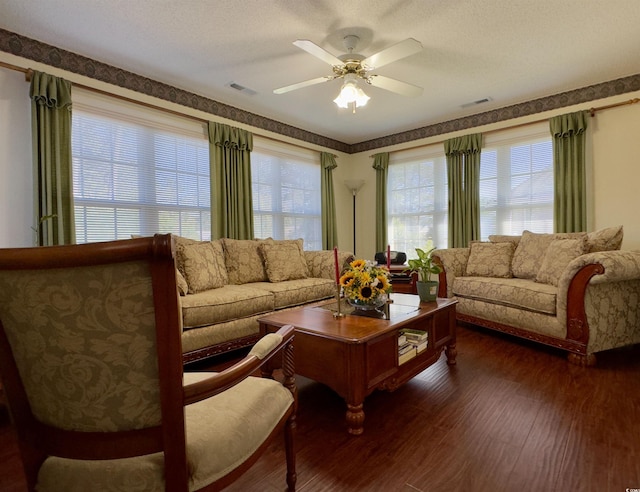 living room with dark wood-type flooring, ceiling fan, and a textured ceiling