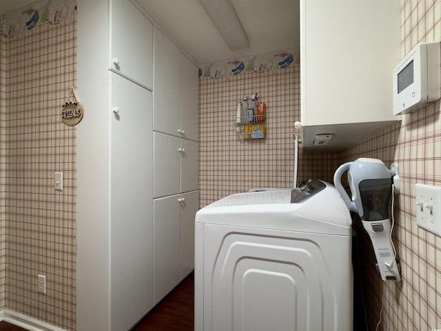 washroom with dark wood-type flooring, washing machine and clothes dryer, and cabinets