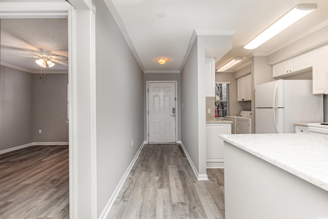 interior space featuring washer and clothes dryer, light wood-type flooring, ornamental molding, and a textured ceiling