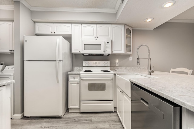 kitchen featuring washing machine and dryer, white cabinetry, sink, and white appliances