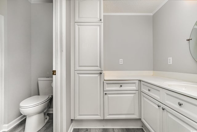 bathroom with toilet, hardwood / wood-style floors, a textured ceiling, crown molding, and vanity