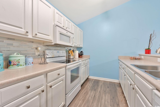 kitchen featuring white appliances, white cabinetry, sink, light hardwood / wood-style flooring, and tasteful backsplash