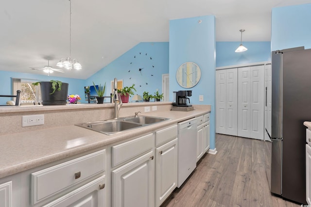 kitchen with dishwasher, vaulted ceiling, white cabinets, decorative light fixtures, and sink