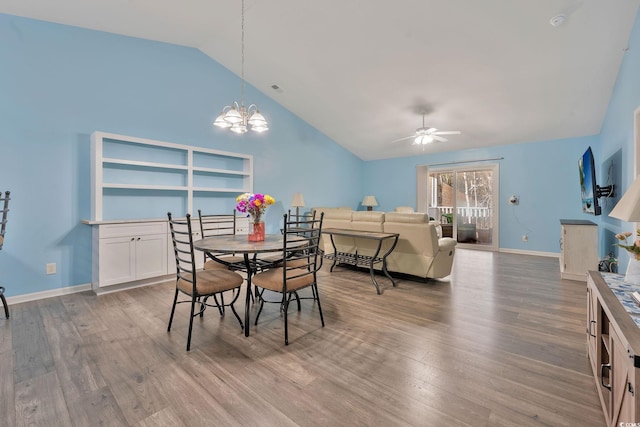 dining space featuring ceiling fan with notable chandelier, vaulted ceiling, and hardwood / wood-style floors