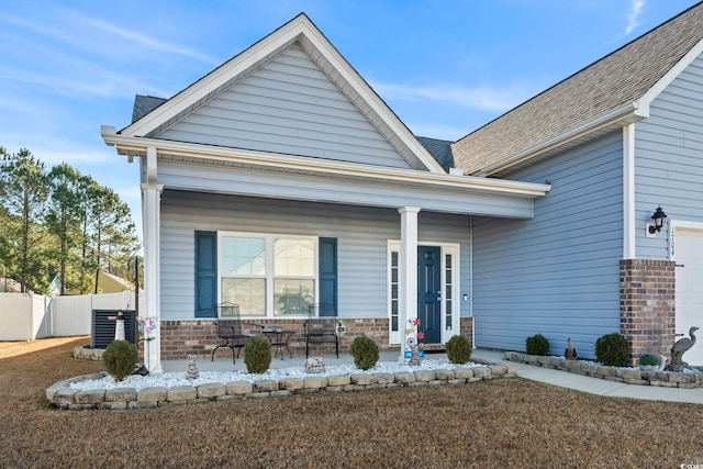 view of front of house featuring covered porch, central AC unit, and a garage