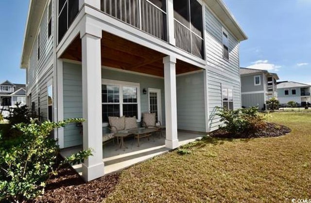 rear view of property featuring a lawn and a patio