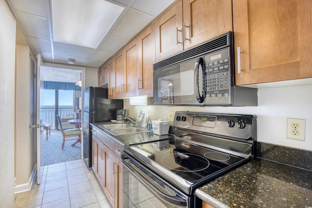 kitchen with a drop ceiling, light tile patterned floors, electric range, dark stone countertops, and sink