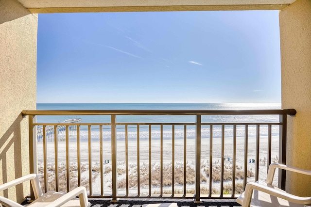 balcony with a water view and a view of the beach