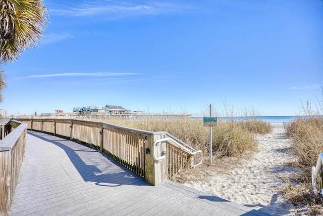 wooden terrace with a water view and a view of the beach