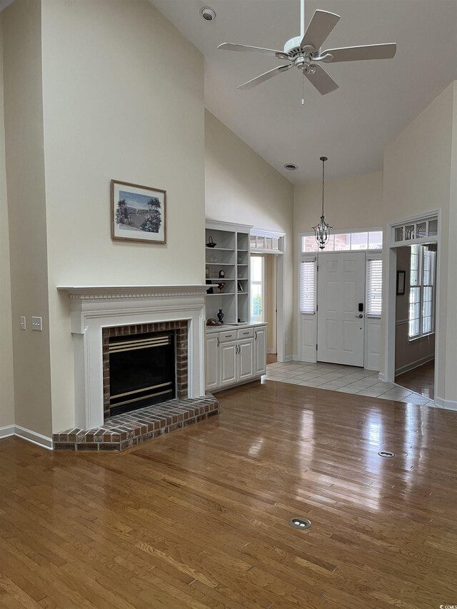 unfurnished living room with dark hardwood / wood-style flooring, a skylight, high vaulted ceiling, and ceiling fan with notable chandelier