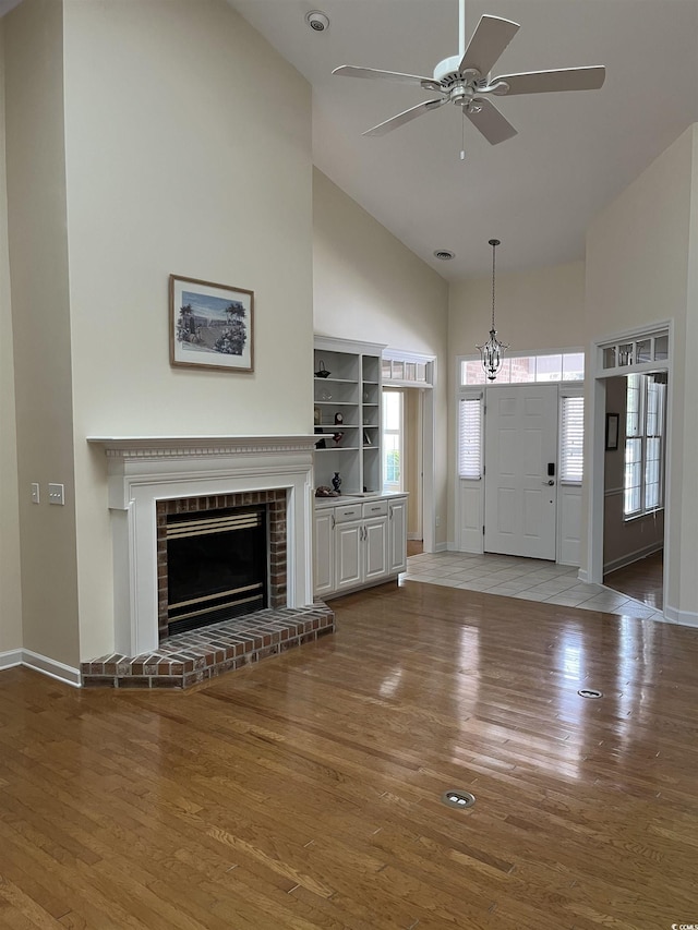 interior space featuring a brick fireplace, a healthy amount of sunlight, hardwood / wood-style floors, and high vaulted ceiling