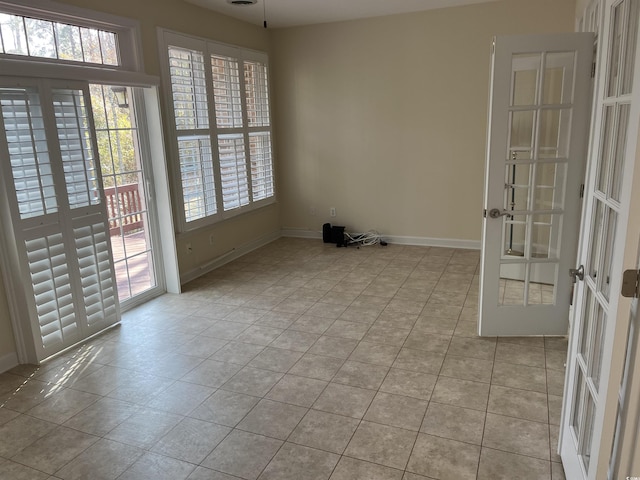 tiled empty room featuring french doors