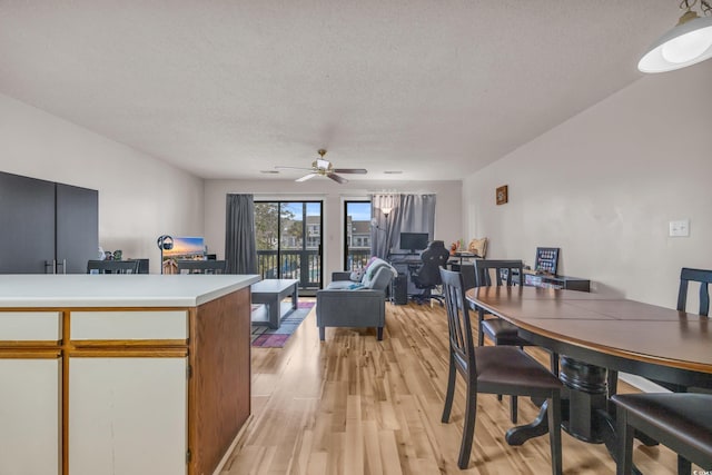 dining space featuring a textured ceiling, light wood-type flooring, and a ceiling fan