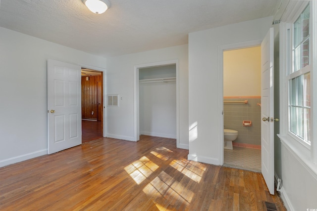 unfurnished bedroom with a closet, hardwood / wood-style floors, tile walls, and a textured ceiling