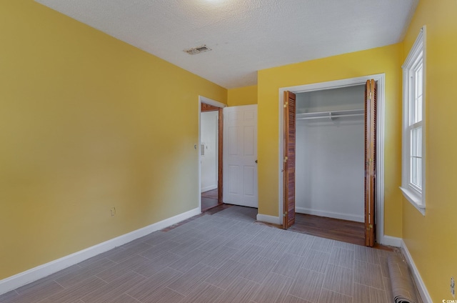 unfurnished bedroom with hardwood / wood-style flooring, a closet, and a textured ceiling