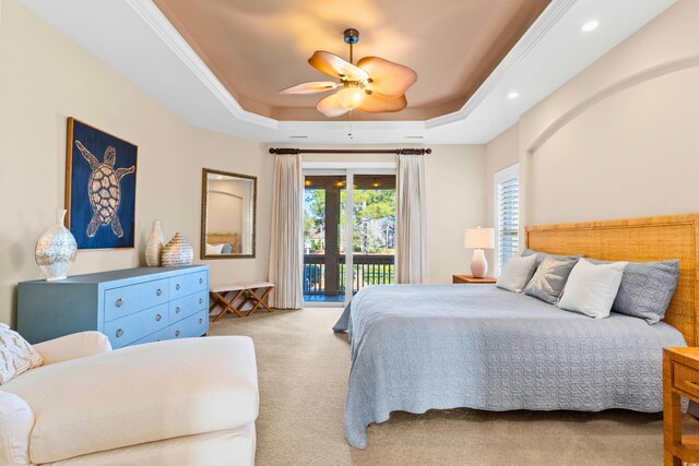 carpeted bedroom featuring ceiling fan, access to exterior, a tray ceiling, and ornamental molding