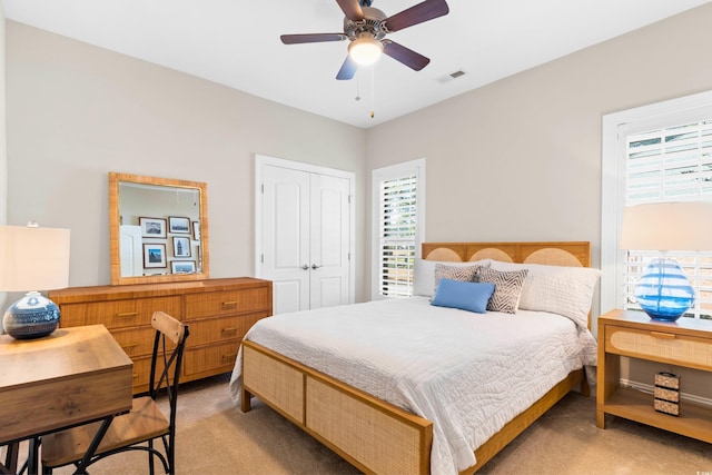 bedroom with ceiling fan, light colored carpet, and a closet