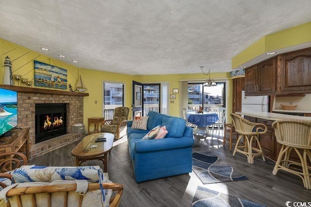 living room featuring a textured ceiling, a brick fireplace, and dark hardwood / wood-style floors