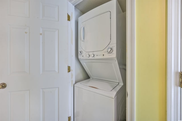 washroom featuring stacked washer and clothes dryer and a textured ceiling